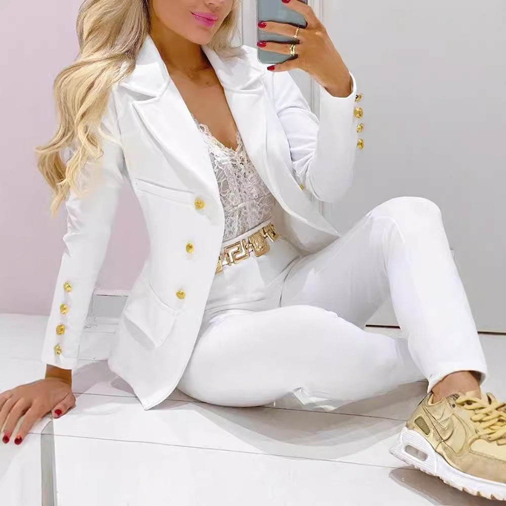 Woman in a white suit with gold accents sitting on a white surface.